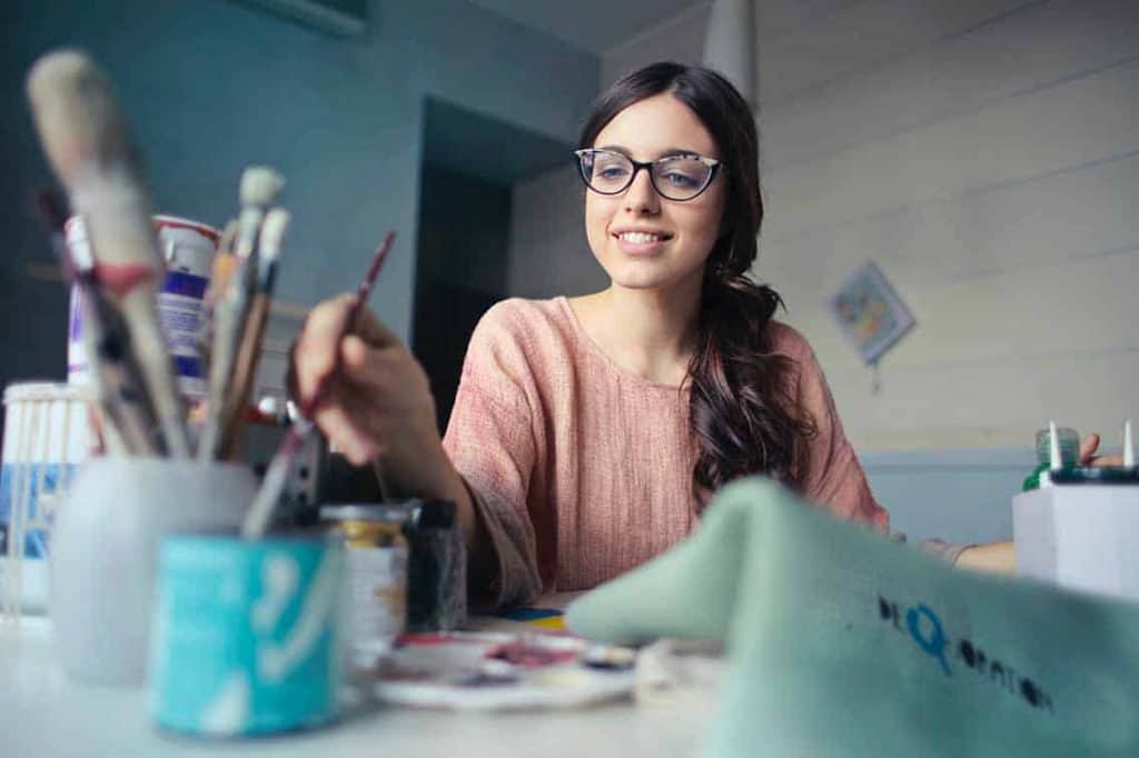 Une femme sourit et prend un pinceau