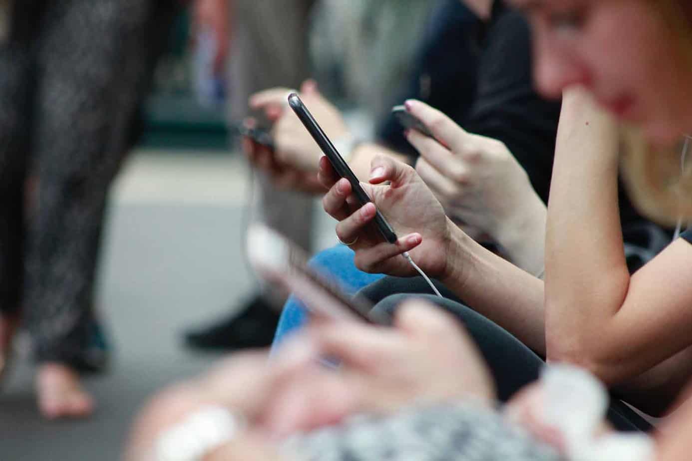 Plusieurs personnes assises à l'extérieur regardent leur téléphone portable